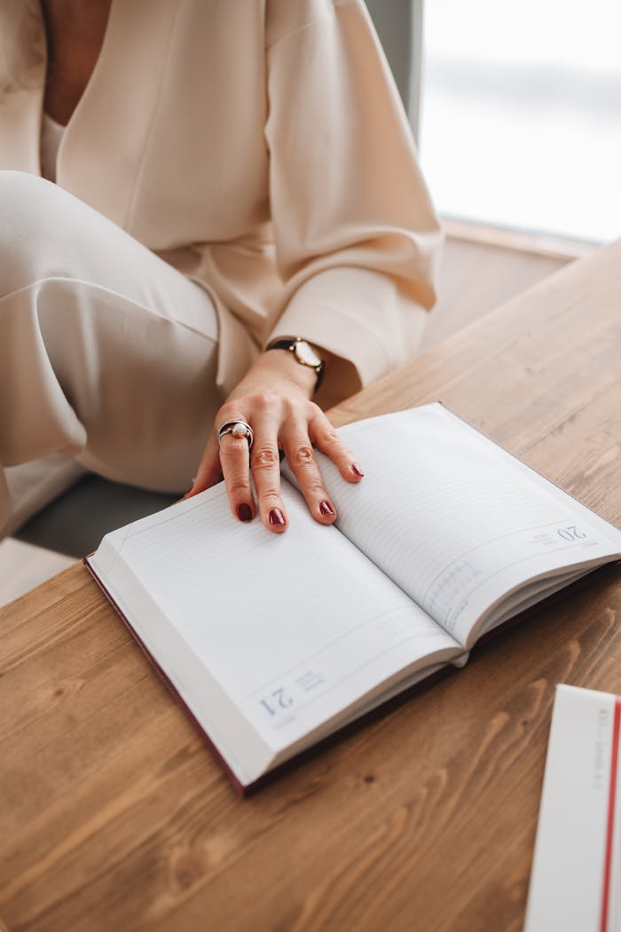 The Art of Drawing Readers In: Your attractive post title goes here Close-up of a woman's hand on an open diary on a wooden table, capturing an intimate reading moment indoors.